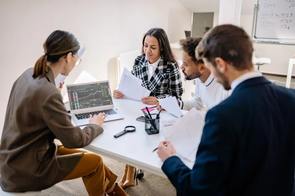 Colleagues reviewing information together on a laptop during an office meeting.