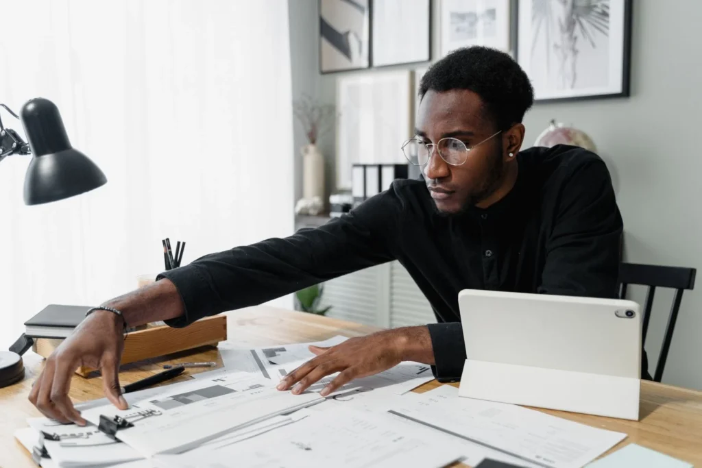 Professional reviewing financial documents and tablet at a desk
