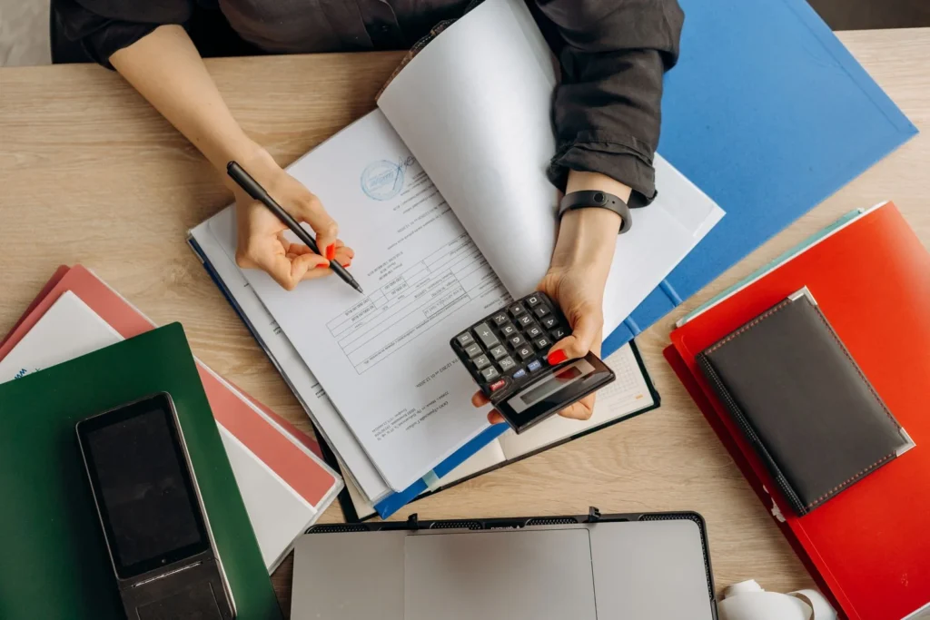 Person reviewing documents with a calculator at a desk