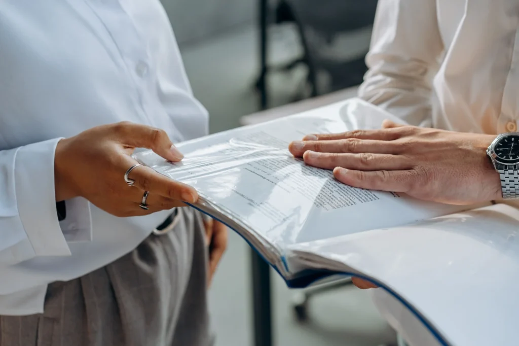 Two people reviewing a binder of documents together at a desk