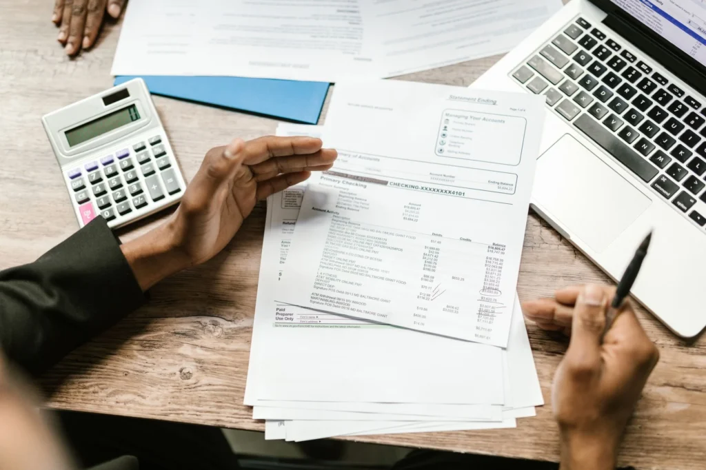 Printed financial papers, a calculator and a laptop on a desk